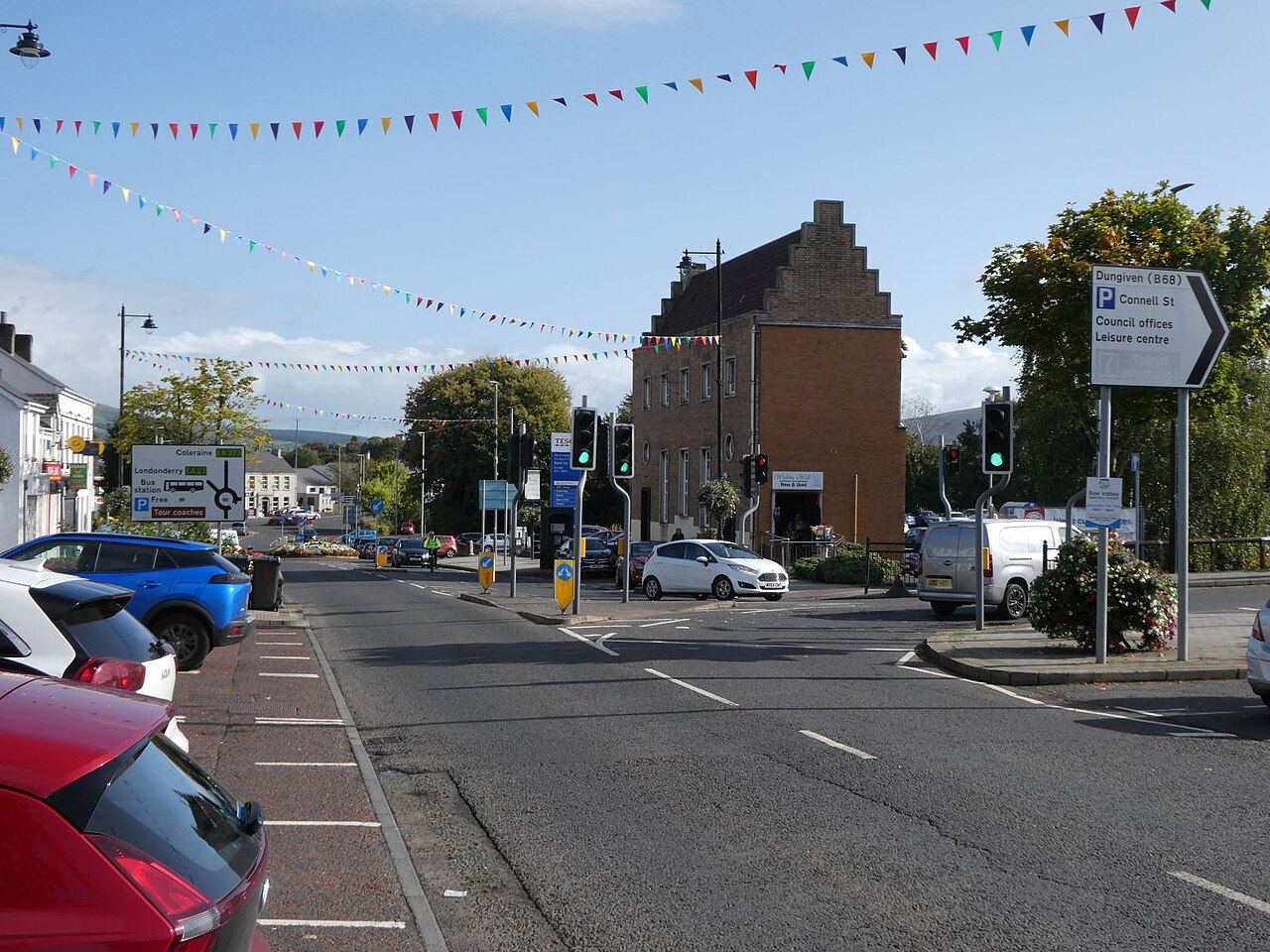 A junction on Main Street in Limavady with traffic lights, bunting across the road and a red-brick building on the corner