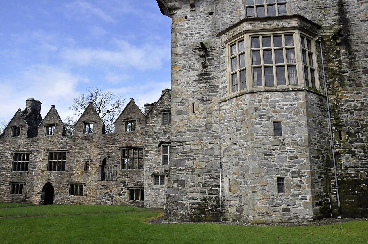 Stone tower and gabled Jacobean wing of Donegal Castle behind a green lawn