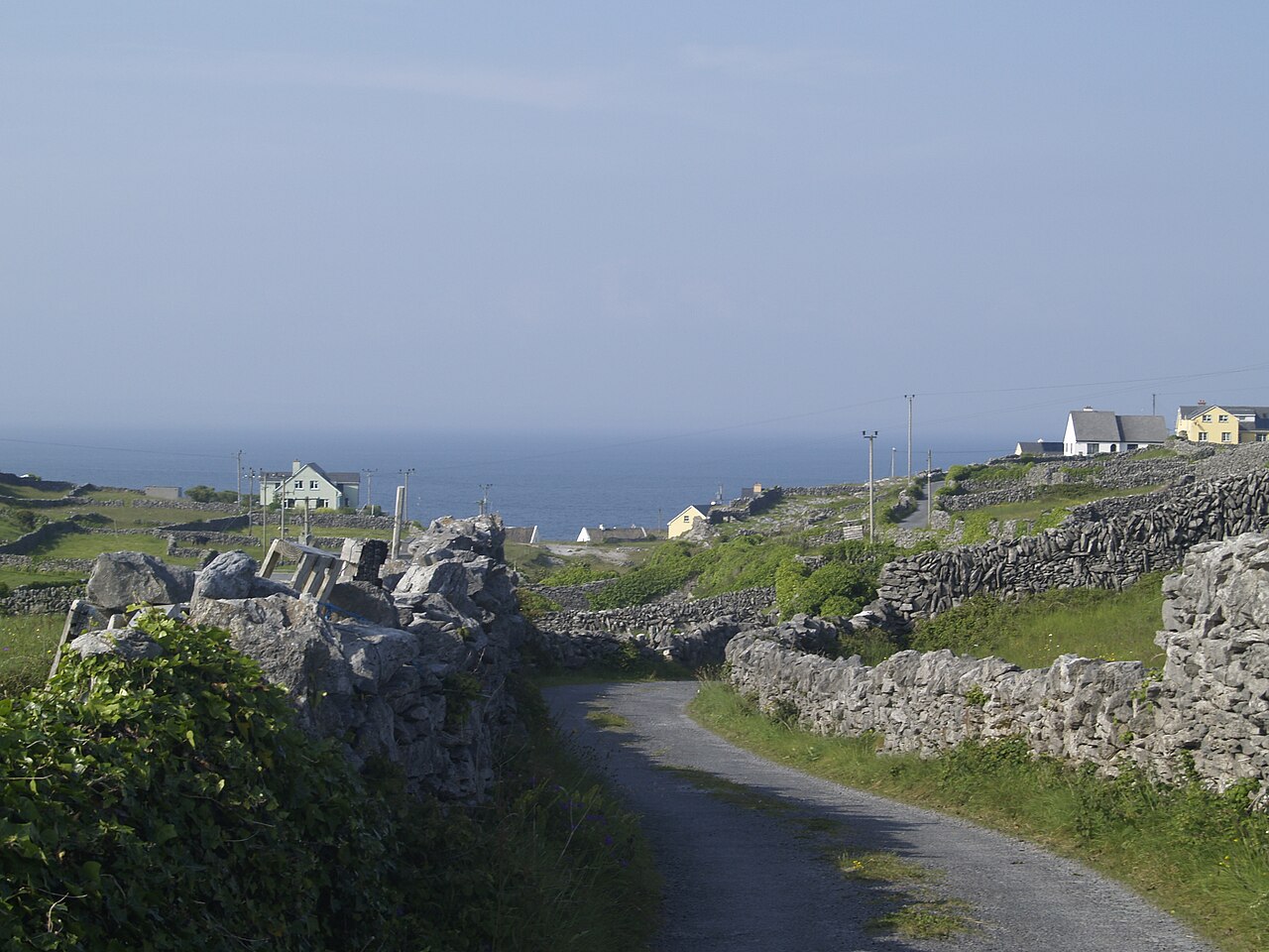 Narrow road between limestone walls on Inis Oírr, with the sea behind