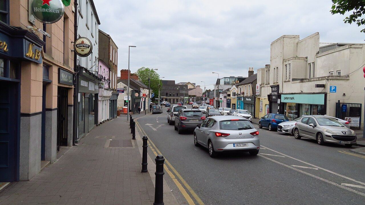 Shopfronts and parked cars along North Main Street in Naas on a grey day
