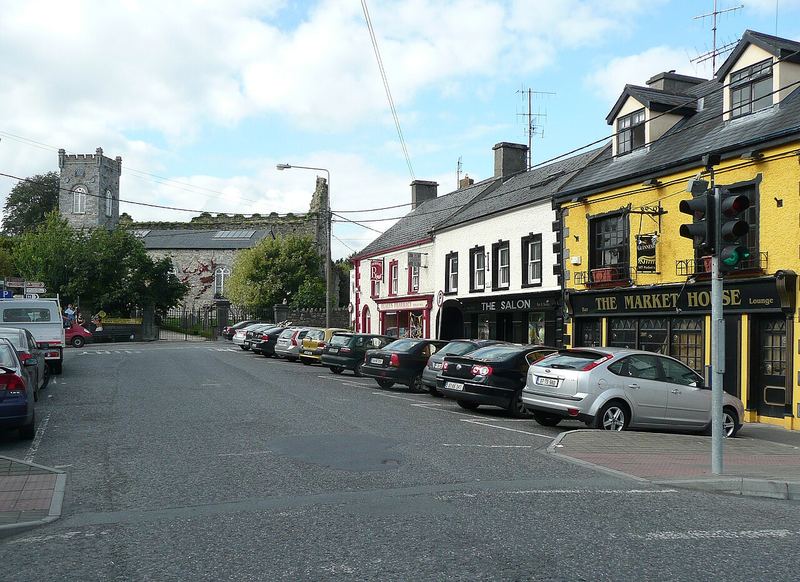 Parked cars along Market Street, Thomastown, with The Market House pub and the church tower behind