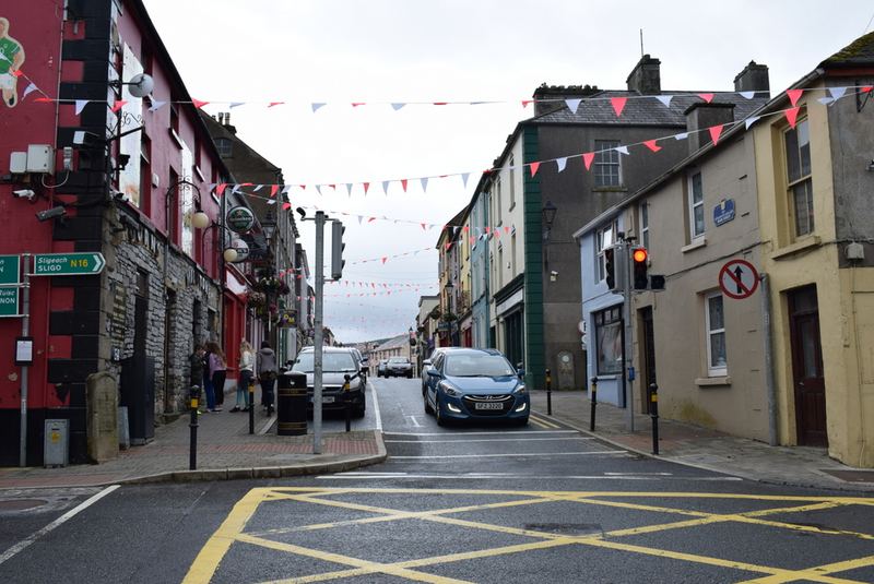Main Street in Manorhamilton with bunting strung between shopfronts and a car at the junction