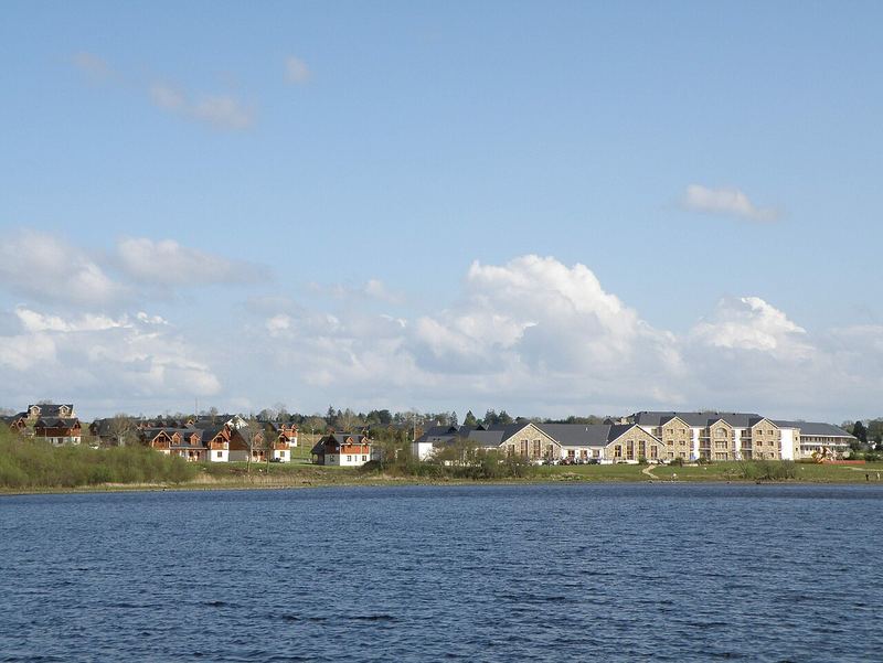 Lough Allen under a blue sky, with houses and a large hotel building on the Drumshanbo shore
