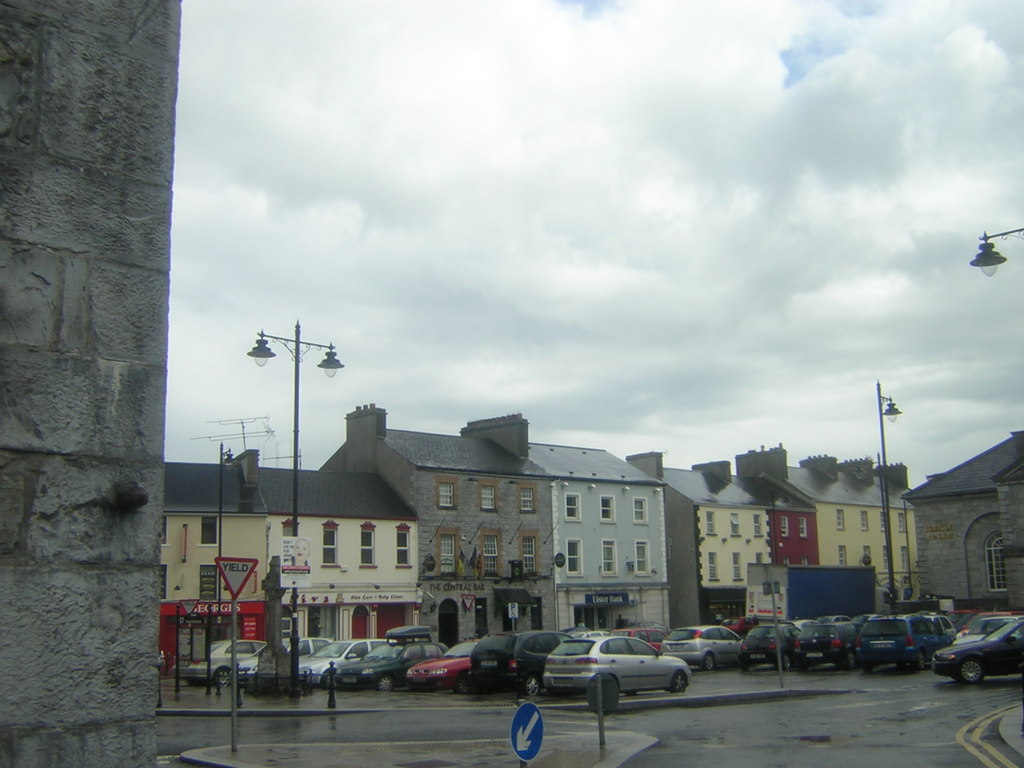 The Square in Roscommon town on an overcast day, with shops, parked cars and a stone wall in the foreground