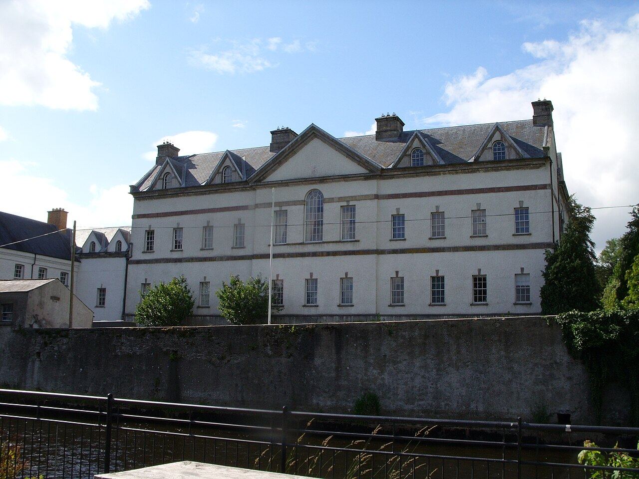 King House, a three-storey Georgian mansion in Boyle, seen from across the Boyle River behind a stone wall