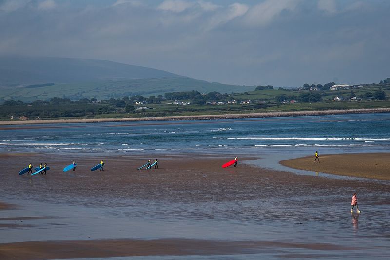 Surfers carrying boards across the sand at Strandhill at low tide
