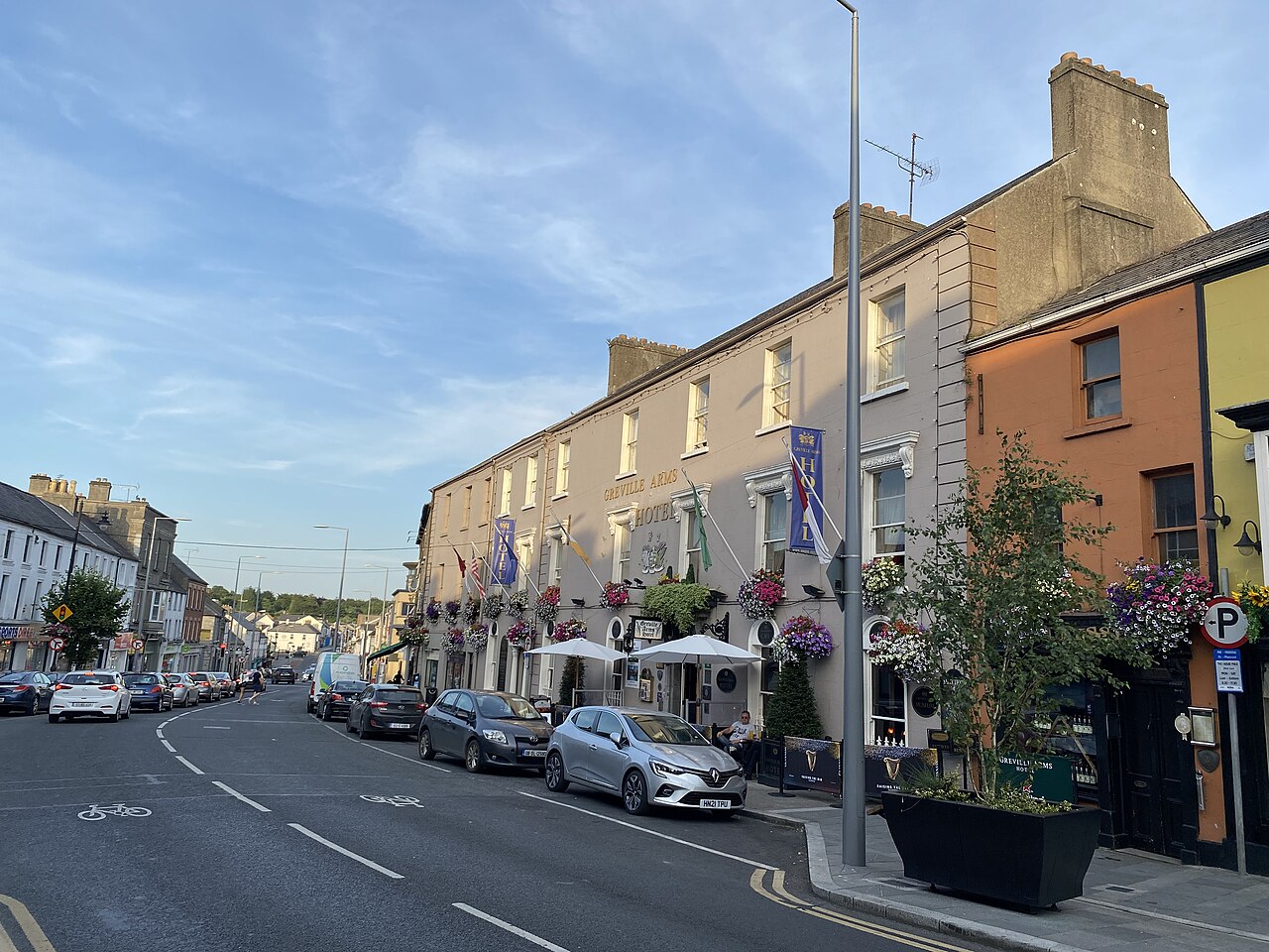 Pearse Street in Mullingar with parked cars and hanging baskets on a hotel front